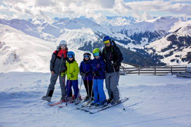Aile, güneşli bir günde kayak merkezinde kayak yapmak, manzaranın tadını çıkarmak.