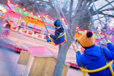 Çocuk, sevimli çocuk gün batımında salıncakta sallanıyor, hareket bulanıklığı, renkli bir arka plan.