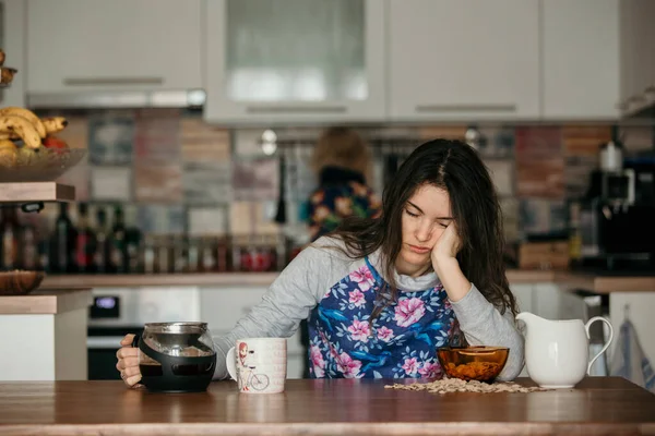 疲れて母親は 午前中にコーヒーを注ぐしようとする 眠れない夜の後台所のテーブルの上に寝そべってコーヒーを飲みに — ストック写真