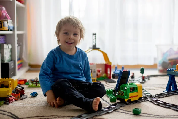 可爱的小男孩在家里玩五颜六色的塑料建筑块 坐在地板上 乘火车行驶在铁路上 儿童创意游戏 — 图库照片