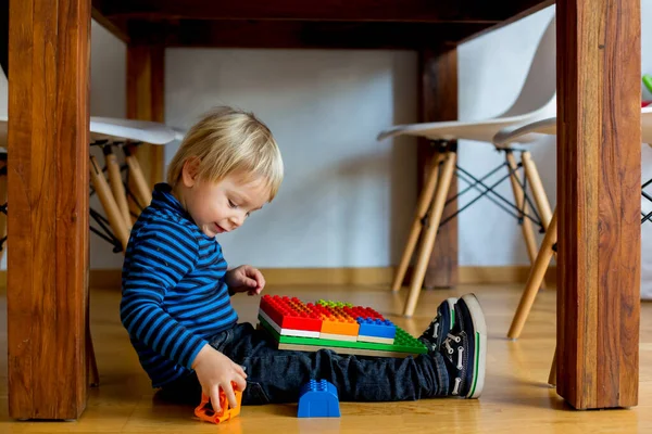 テーブルの下の床に座って 自宅でカラフルなプラスチック製の建設ブロックで遊んで愛らしい小さな男の子 子供のための創造的なゲーム — ストック写真