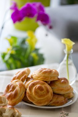 Ekmek çörekleri tabakta, vazo vazoda çiçekli.