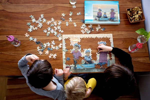 3人の子供 男の子 ビーチからの写真でパズルを組み立て 一緒に家で遊ぶ — ストック写真