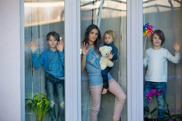 Family, standing behind the window, at home, quarantine due to coronavirus