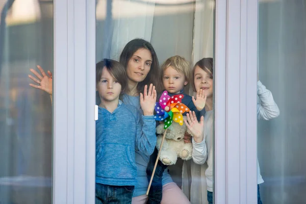 Family, standing behind the window, at home, quarantine due to coronavirus