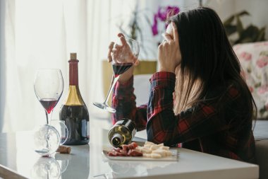 Üzgün, yorgun bir kadın, evde şarap içiyor, yalnız, oturma odasında yerde oturuyor, depresyonda.