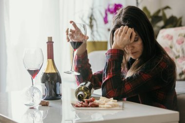 Üzgün, yorgun bir kadın, evde şarap içiyor, yalnız, oturma odasında yerde oturuyor, depresyonda.
