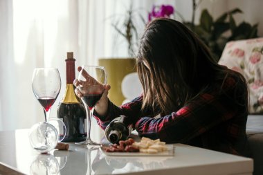 Üzgün, yorgun bir kadın, evde şarap içiyor, yalnız, oturma odasında yerde oturuyor, depresyonda.