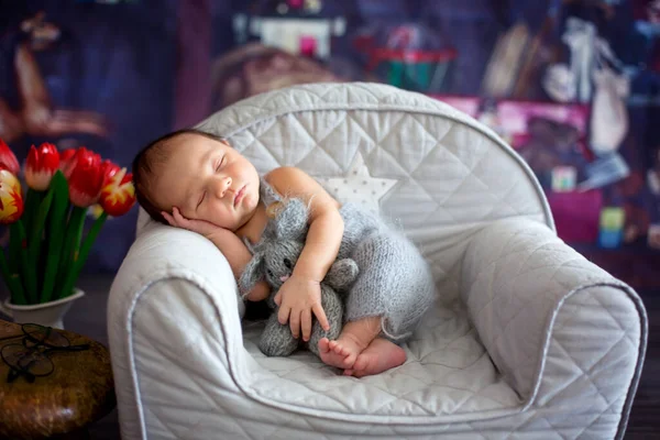 小さな新生児の男の子 小さなニットのおもちゃで小さな居心地の良いベビーアームチェアで寝て 快適な眠り — ストック写真
