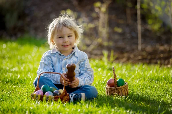 Kleiner Junge Isst Schokohase Garten Bei Sonnenuntergang Ostereier Ihn Herum — Stockfoto