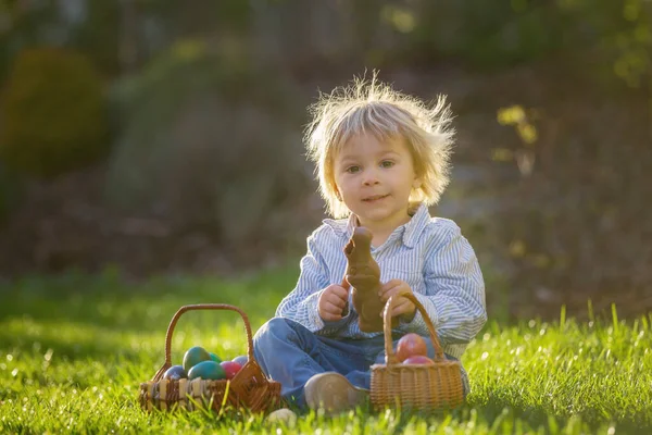 Μικρό Αγοράκι Τρώει Σοκολατένιο Λαγουδάκι Στον Κήπο Ηλιοβασίλεμα Αυγά Πασχαλιάς — Φωτογραφία Αρχείου