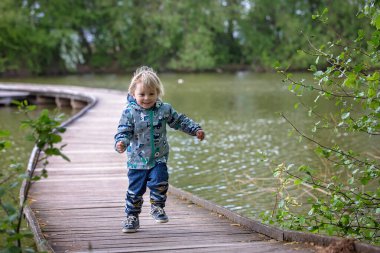 Çocuk, çocuk, bir bahar günü gölün üzerindeki tahta köprüde oturuyor ya da koşuyor.
