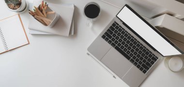Boş dizüstü bilgisayarı ve beyaz ahşap masadaki ofis malzemeleriyle modern ofis odasının en üst görüntüsü. 