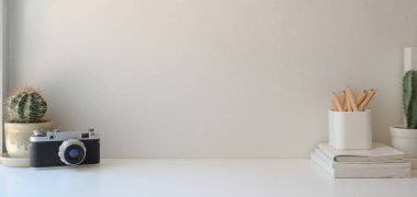 Beyaz ahşap masa ve pembe duvar arkaplanı üzerinde fotokopi alanı ve ofis gereçleri olan minimal işyeri 