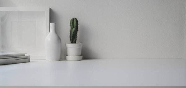 Minimal office room with copy space and decorations on white wooden table and cactus pot 