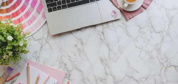 Gambar di atas kepala ruang kerja desainer feminin merah muda dengan komputer laptop dan alat-alat melukis di latar belakang meja marmer — Stok Foto