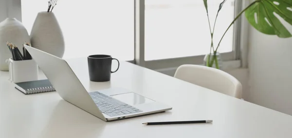 Gemütliches Arbeitszimmer mit Laptop und Büromaterial auf weißem Holztisch in der Nähe der Fenster — Stockfoto