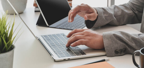 Обрезанный снимок профессионального бизнесмена, печатающего на ноутбуке во время работы над проектом
 