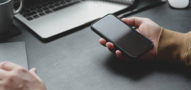 Profesyonel iş adamının akıllı telefon tutarken çekilmiş görüntüsü.