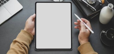 Karanlık, modern işyerinde çalışırken boş ekran tableti kullanan bir adamın yakın plan görüntüsü 
