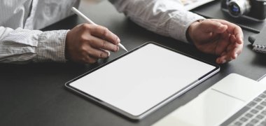 Proje üzerinde çalışan profesyonel iş adamının karanlık modern ofis odasında boş ekran tabletle çekilmiş görüntüsü. 