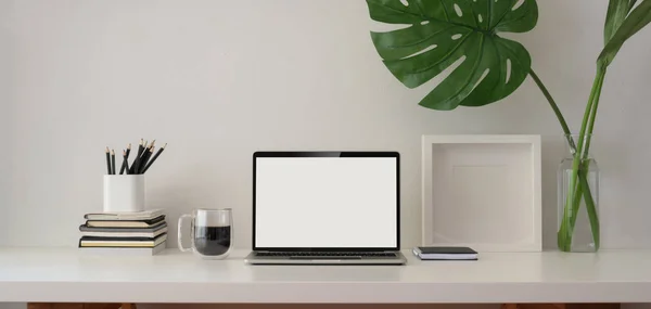 Hipster lugar de trabajo con ordenador portátil de pantalla en blanco con maqueta de marco y suministros de oficina en la mesa de madera blanca —  Fotos de Stock