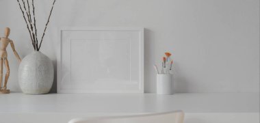 Beyaz masa üzerinde beyaz duvar arkaplanı olan seramik süslemeleri olan küçük çerçeve ile oda 