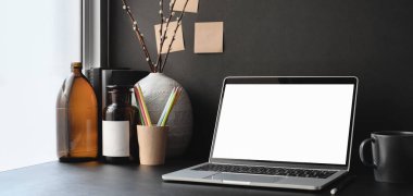 Boş dizüstü bilgisayarı ve dekorasyonlu ofis malzemeleri olan karanlık moda ofis odası. 