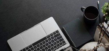 Dizüstü bilgisayarı ve fotokopi alanı olan ofis malzemeleriyle karanlık ve modaya uygun iş yerlerinin üst görünümü 