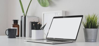 Modern ofis odasının boş ekran bilgisayar ve ofis malzemeleriyle beyaz masa üzerinde kırpılmış görüntüsü. 