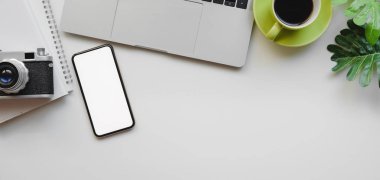 Dizüstü bilgisayarlı en iyi iş yeri görüntüsü, beyaz masa arkaplanındaki akıllı telefon ve kamera modelleri
