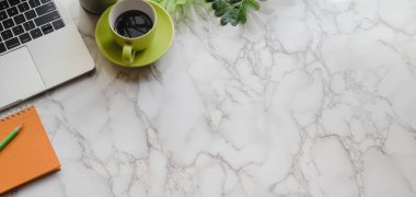 Ofis malzemeleri ve yeşil kahve fincanı mermer masa arkasında modern iş yeri manzarası.
