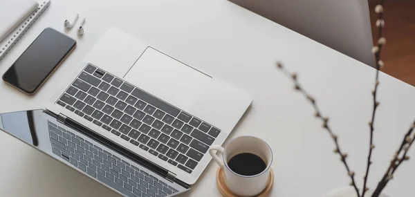 Abgeschnittene Aufnahme eines komfortablen Arbeitsplatzes mit Laptop und Büromaterial auf weißem Holztisch — Stockfoto