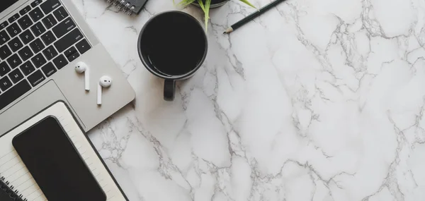 Top view of stylish workspace with laptop computer, smartphone and office supplies on marble desk background