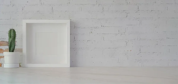 Montar marco con pote de cactus en la habitación de oficina mínima en la mesa blanca y fondo de pared de ladrillo blanco —  Fotos de Stock