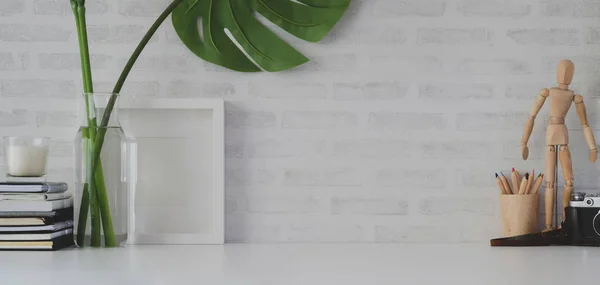 Lieu de travail confortable avec un cadre maquillé et des fournitures de bureau sur une table blanche et un mur de briques blanches — Photo