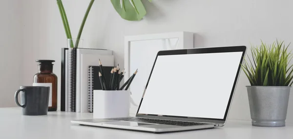 Imagen recortada de la sala de oficina moderna con computadora portátil de pantalla en blanco y suministros de oficina en la mesa blanca —  Fotos de Stock