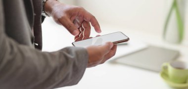 Modern ofis odasında akıllı telefonunu kullanan başarılı bir iş adamının görüntüsü. 