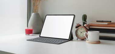 Beyaz masa üzerinde boş ekran dijital tableti ve ofis malzemeleri olan çağdaş iş yeri 