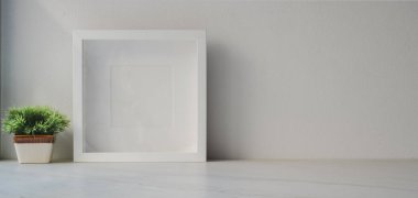 Beyaz ahşap masa üzerinde çerçeve ve ağaç demliği oluşturan en az çalışma alanı ve kopya alanı olan beyaz duvar arkaplanı 