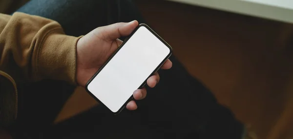 Närbild av mannen som håller blank skärm smartphone medan sitter hans bekväma kontorsrum — Stockfoto