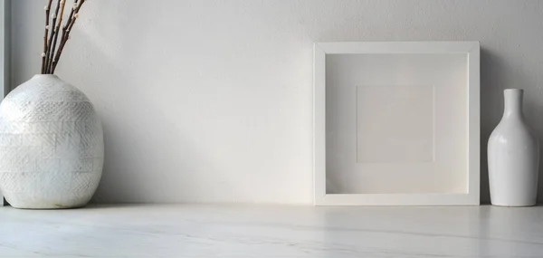 Imagen recortada de espacio de trabajo mínimo con marco simulado y decoraciones de jarrones de cerámica en mesa de madera blanca con espacio de copia —  Fotos de Stock