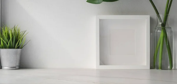 Captura recortada de espacio de trabajo mínimo con marco simulado y maceta de árbol en mesa de madera blanca y fondo de pared blanco con espacio de copia —  Fotos de Stock