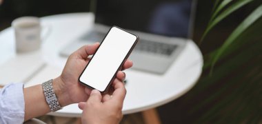 Açık havada iş yerinde projesinde çalışırken akıllı telefonunu kullanan bir adamın görüntüsü. 