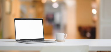 Laptop bilgisayarı ve ofis geçmişi olan kahve fincanıyla rahat bir iş yeri. 
