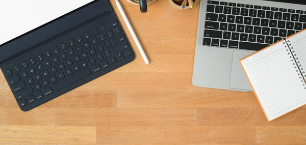 Top view of modern workspace with laptop computer and tablet with office supplies on wooden table with copy space