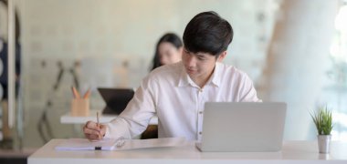 Modern ofis odasındaki projesinde çalışan genç profesyonel iş adamının kırpılmış görüntüsü. 
