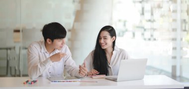 Genç profesyonel grafik ekibi modern ofis odasında projeyi tartışıyor. 