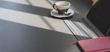 Modern ofis odası dijital tablet ve ofis malzemeleriyle koyu gri masa üzerinde fotokopi alanı ve güneş ışığı ile 