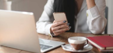 Akıllı telefondan bilgi ararken iş kadınının şu anki projesi üzerinde çalışmasının yakın plan görüntüsü